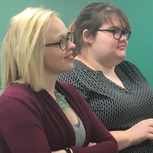 Two people looking towards a speaker